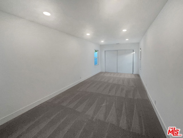 unfurnished room featuring dark colored carpet