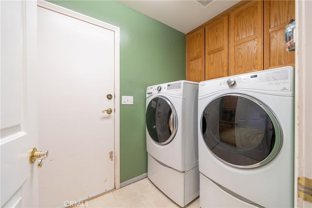 clothes washing area featuring cabinets, separate washer and dryer, and light tile patterned floors