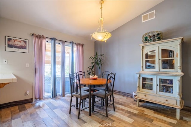 dining room with vaulted ceiling and light hardwood / wood-style flooring