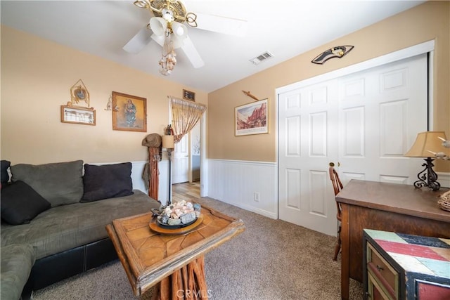 living room featuring carpet flooring, ceiling fan, and wooden walls