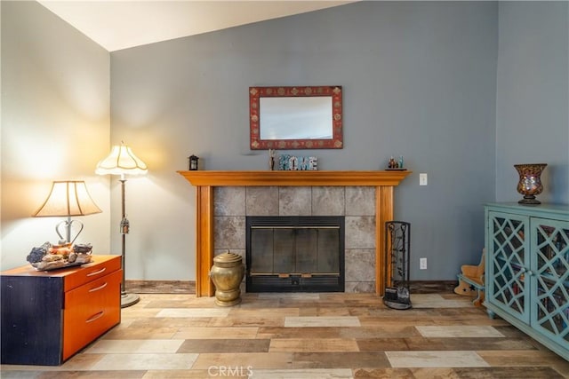 living area with a tile fireplace, light hardwood / wood-style floors, and lofted ceiling