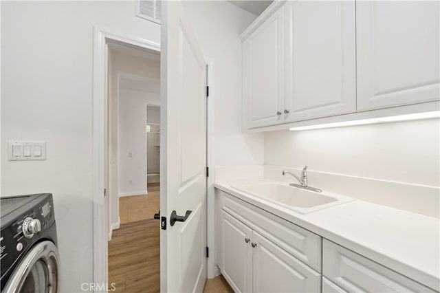 laundry room with washer / dryer, light hardwood / wood-style flooring, sink, and cabinets