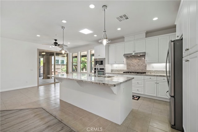 kitchen with an island with sink, white cabinets, pendant lighting, appliances with stainless steel finishes, and ceiling fan