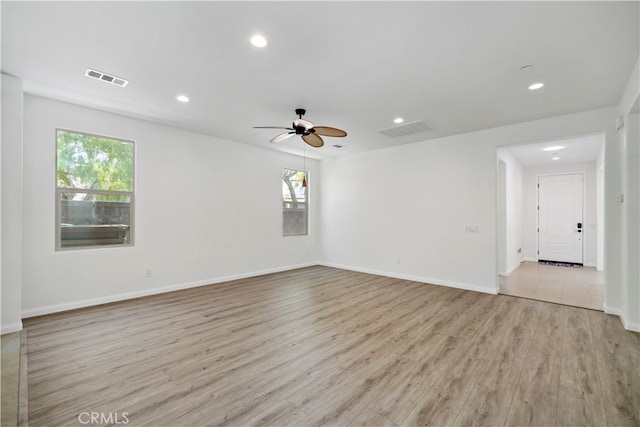 empty room with ceiling fan, light wood-type flooring, and plenty of natural light