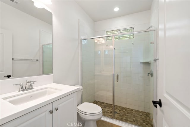 bathroom with vanity, a shower with shower door, and toilet