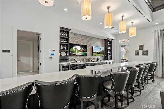 bar featuring decorative backsplash, hanging light fixtures, light wood-type flooring, and beverage cooler