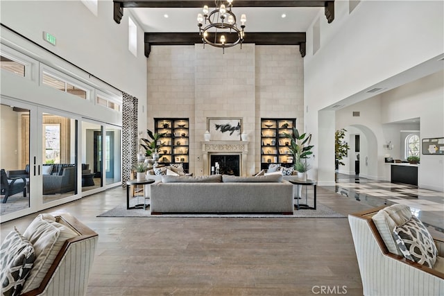 living room featuring beam ceiling, wood-type flooring, and a towering ceiling