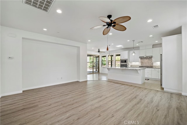 unfurnished living room featuring ceiling fan and light wood-type flooring