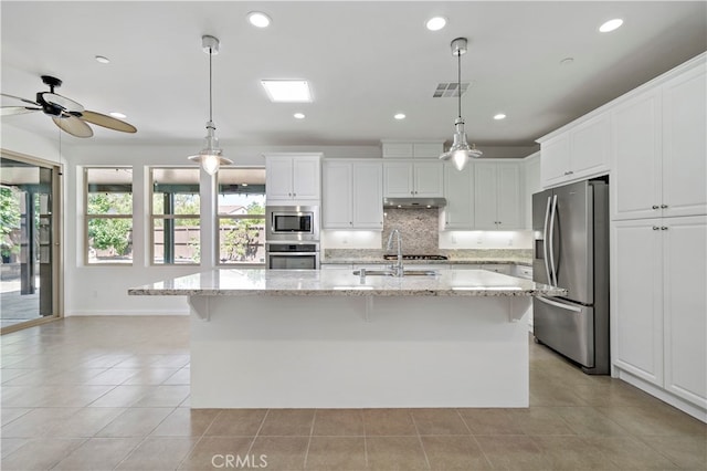 kitchen with white cabinets, a kitchen island with sink, sink, decorative light fixtures, and stainless steel appliances