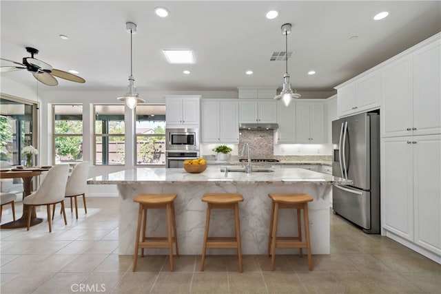 kitchen with hanging light fixtures, a center island with sink, white cabinetry, sink, and stainless steel appliances