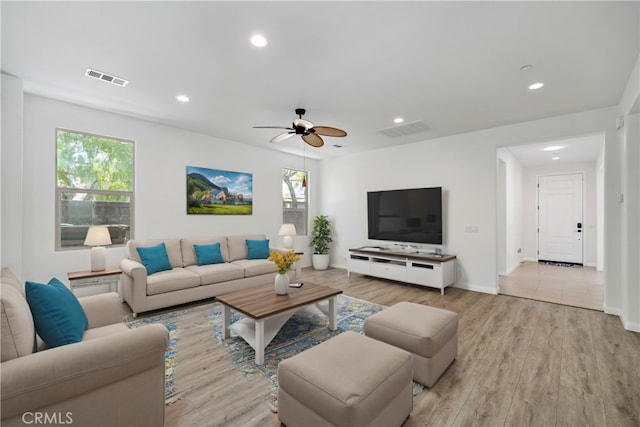 living room featuring a healthy amount of sunlight, light hardwood / wood-style floors, and ceiling fan