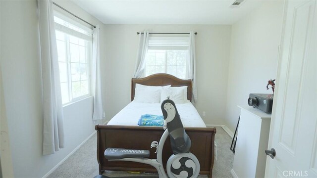 bedroom with light colored carpet and multiple windows