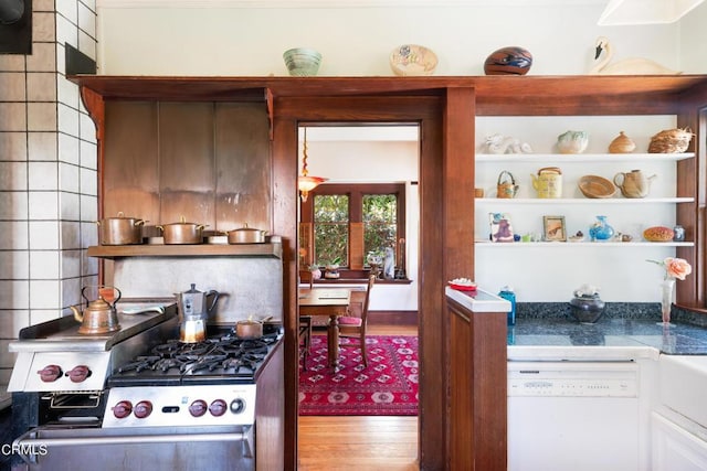 kitchen featuring dishwasher, hardwood / wood-style floors, high end range, and backsplash