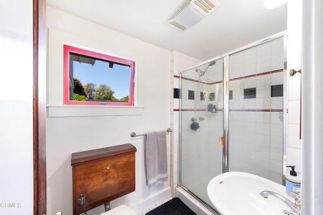 bathroom with a shower with door and sink