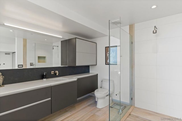 bathroom with wood-type flooring, an enclosed shower, backsplash, toilet, and vanity