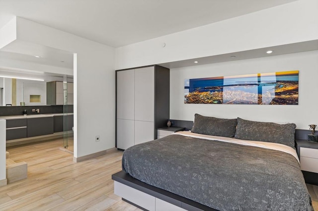 bedroom with sink, connected bathroom, and light hardwood / wood-style floors