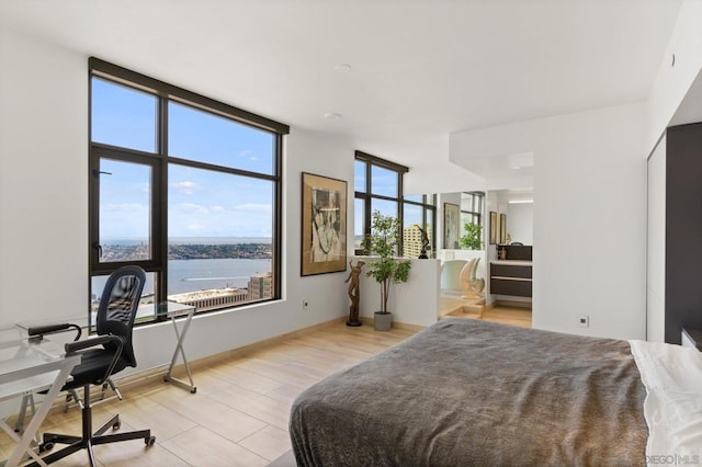 bedroom with a water view and light hardwood / wood-style floors