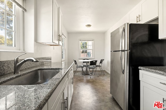 kitchen featuring stainless steel fridge, sink, stone counters, and white cabinetry