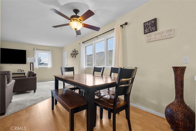 dining area with light wood-type flooring, a mountain view, and ceiling fan