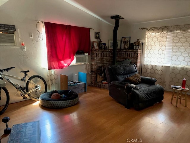 living area with lofted ceiling, plenty of natural light, a wood stove, and hardwood / wood-style floors