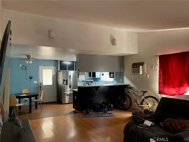 kitchen featuring light hardwood / wood-style floors, kitchen peninsula, stainless steel refrigerator with ice dispenser, ceiling fan, and a wall unit AC