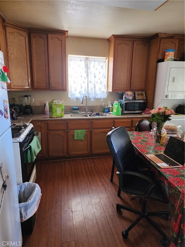 kitchen featuring dark hardwood / wood-style flooring, a textured ceiling, sink, stacked washer / dryer, and white appliances