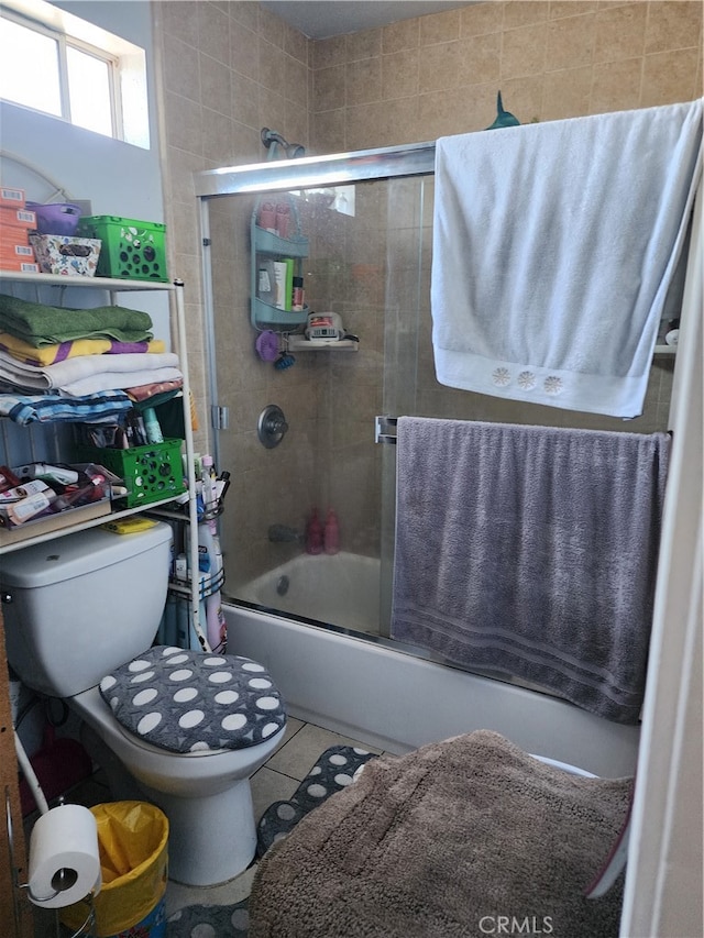 bathroom with toilet, tile patterned floors, and combined bath / shower with glass door