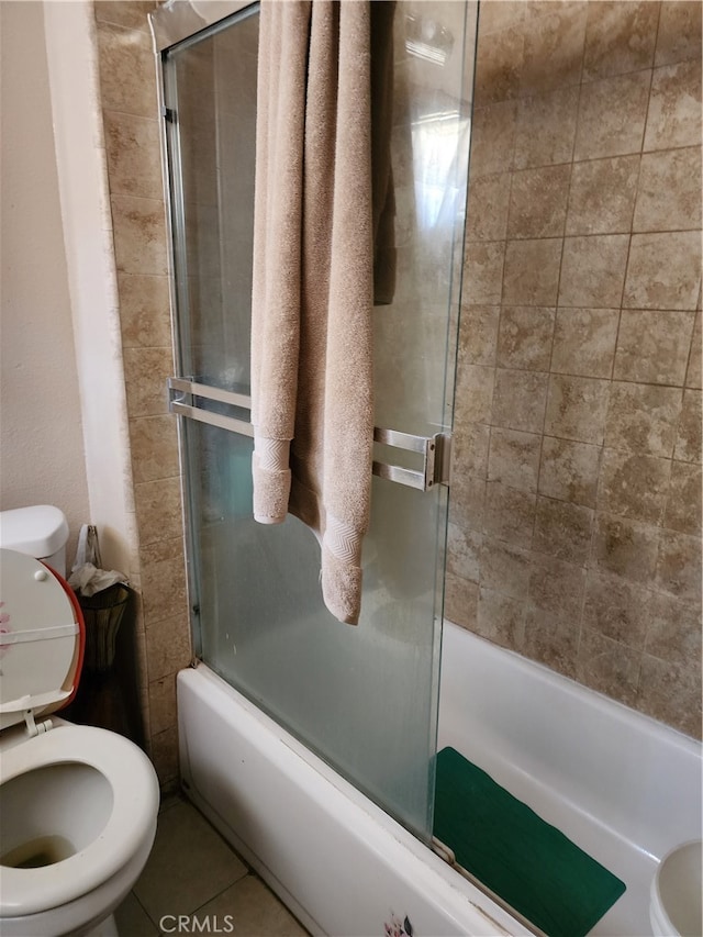 bathroom with bath / shower combo with glass door, toilet, and tile patterned flooring