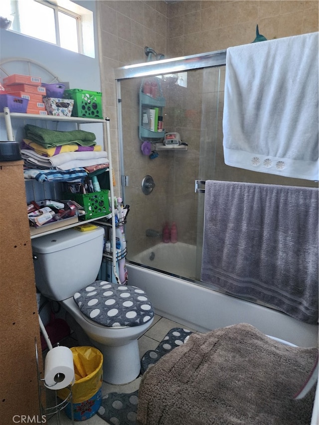 bathroom with toilet, tile patterned floors, and combined bath / shower with glass door