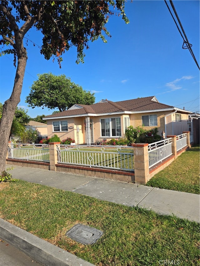 ranch-style home with a front yard, a fenced front yard, and stucco siding