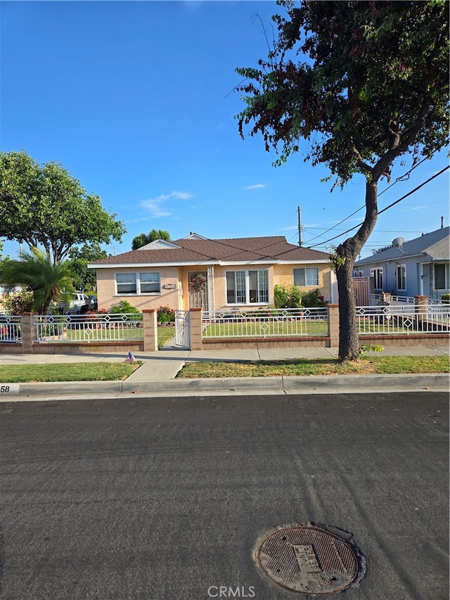 ranch-style house featuring a fenced front yard and stucco siding