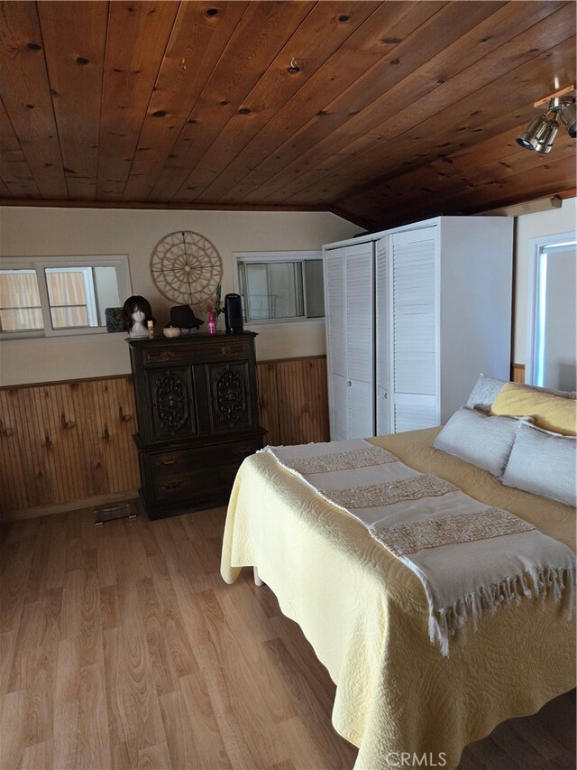 bedroom featuring light wood-style floors, wooden ceiling, wainscoting, and vaulted ceiling