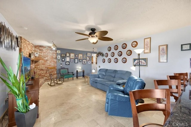 living room with ceiling fan and brick wall