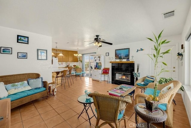 tiled living room with ceiling fan, a textured ceiling, and a tile fireplace