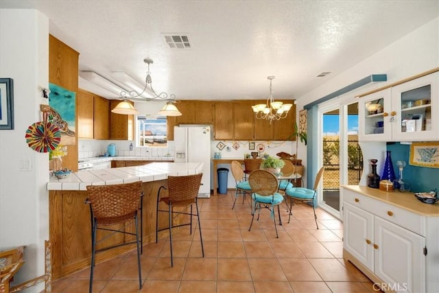 kitchen with white cabinetry, white refrigerator with ice dispenser, kitchen peninsula, and a wealth of natural light