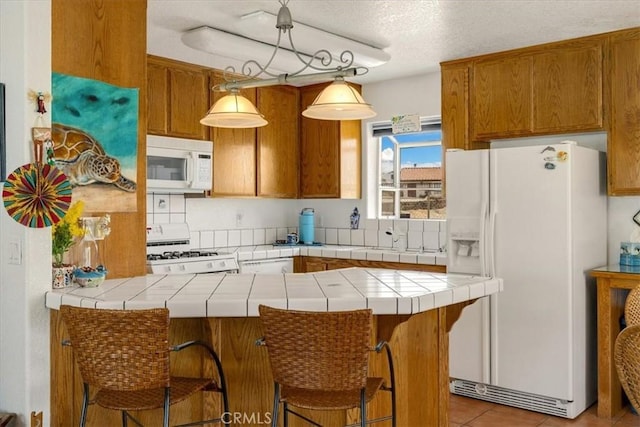 kitchen featuring kitchen peninsula, white appliances, and tile counters