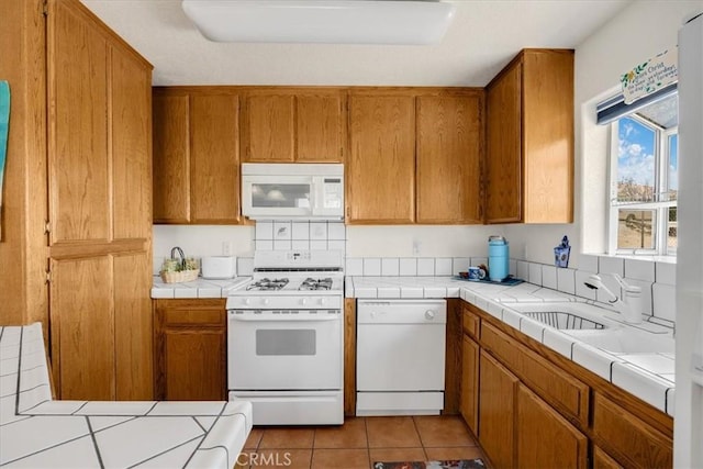 kitchen with light tile patterned floors, white appliances, tile countertops, and sink