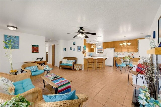 tiled living room with ceiling fan with notable chandelier and a textured ceiling