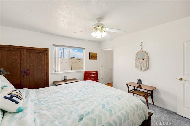 carpeted bedroom with ceiling fan and a textured ceiling