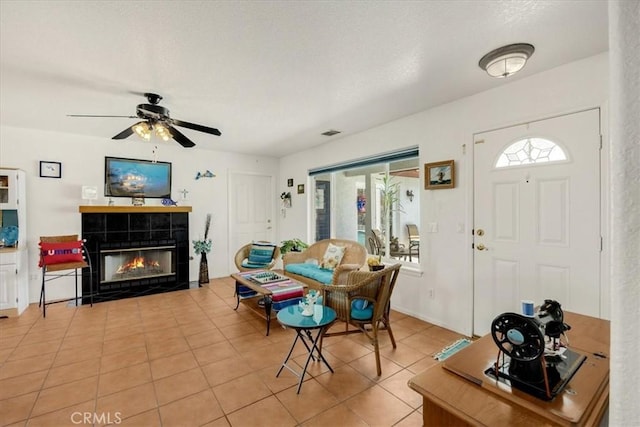 dining area with a tile fireplace, ceiling fan, light tile patterned flooring, and a textured ceiling