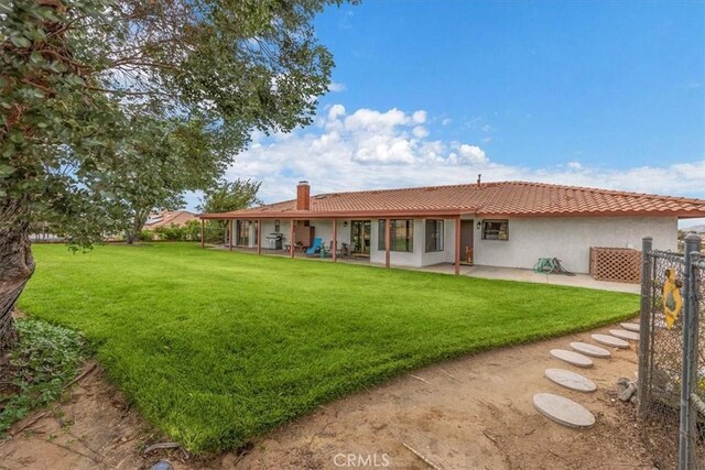 back of property featuring a lawn and a patio