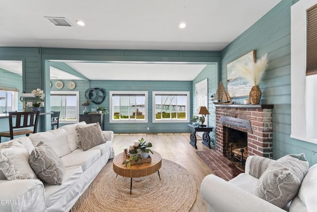 living room featuring wooden walls, a healthy amount of sunlight, vaulted ceiling, and wood-type flooring