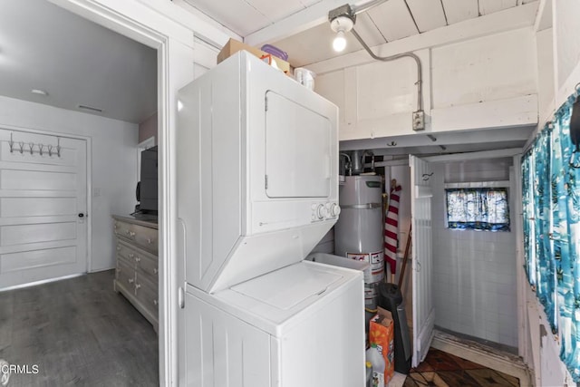 washroom featuring stacked washing maching and dryer, dark wood-type flooring, and water heater