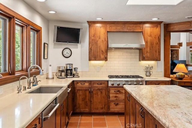 kitchen with wall chimney exhaust hood, appliances with stainless steel finishes, backsplash, and light tile patterned flooring