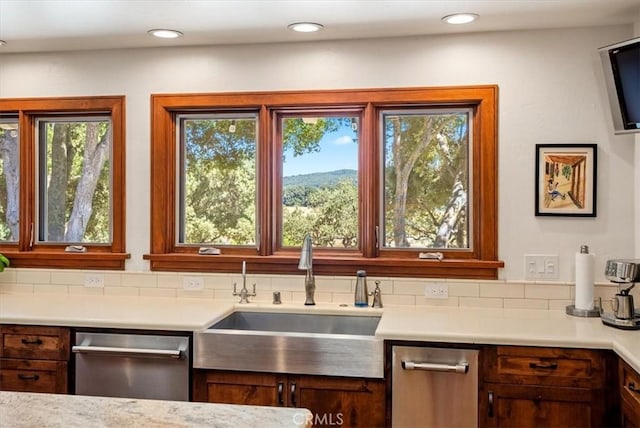 kitchen featuring decorative backsplash, a sink, light countertops, stainless steel dishwasher, and recessed lighting