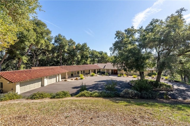 ranch-style home with a garage, a tiled roof, driveway, and stucco siding