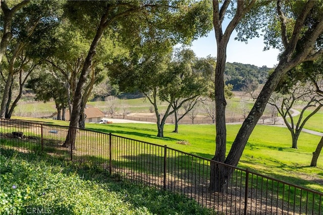 view of property's community with a lawn and fence