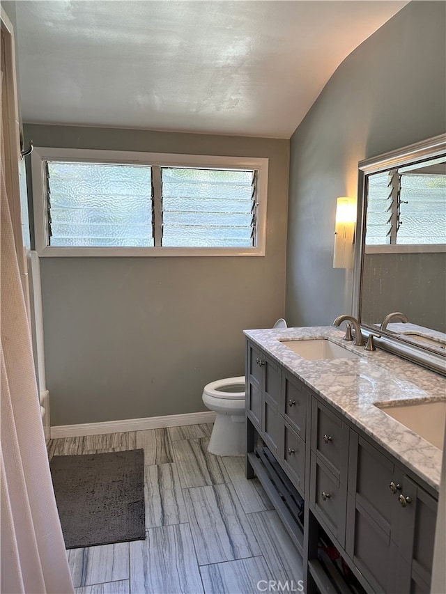 bathroom with vanity, toilet, and vaulted ceiling