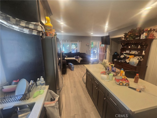 kitchen with light hardwood / wood-style flooring, stainless steel fridge, and a kitchen island