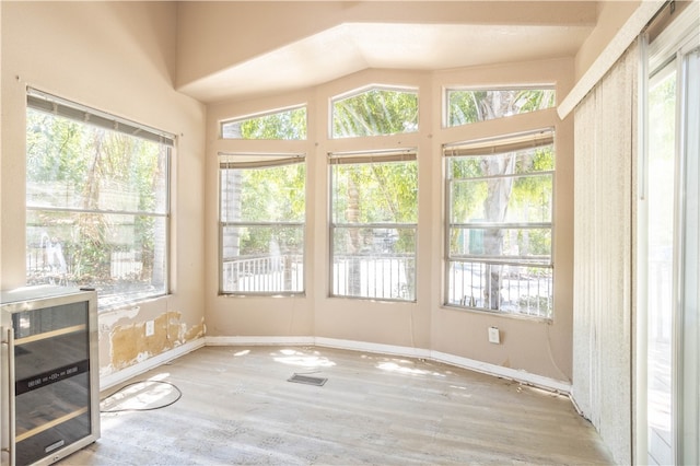 unfurnished sunroom featuring wine cooler, visible vents, and vaulted ceiling